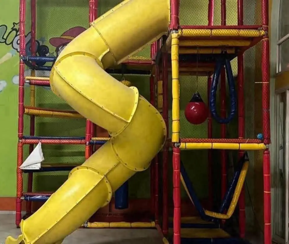 Estructura de juegos con tobogán en espiral amarillo y red para trepar